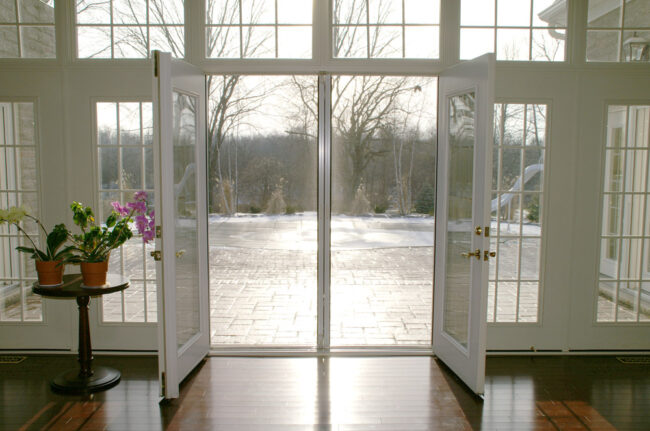 Open glass doors overlooking a calm river with a peaceful outdoor view.