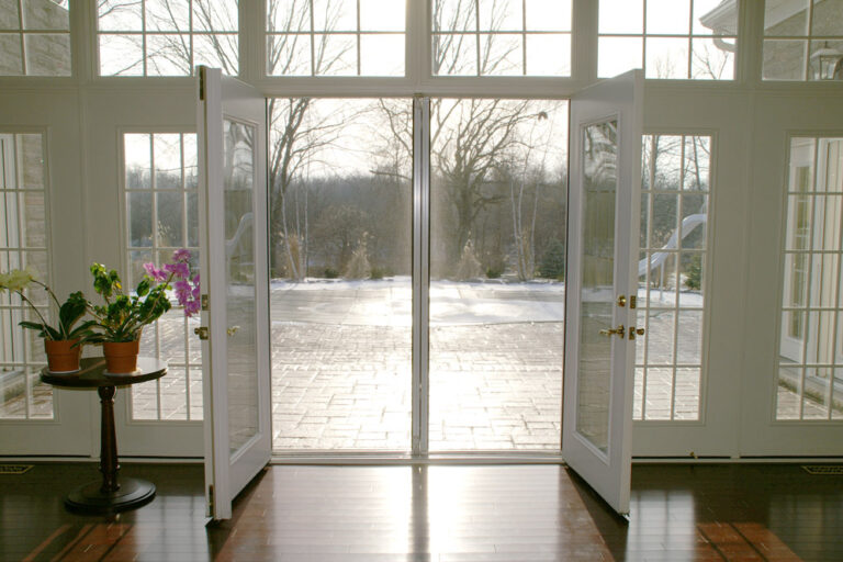 Open glass doors overlooking a calm river with a peaceful outdoor view.