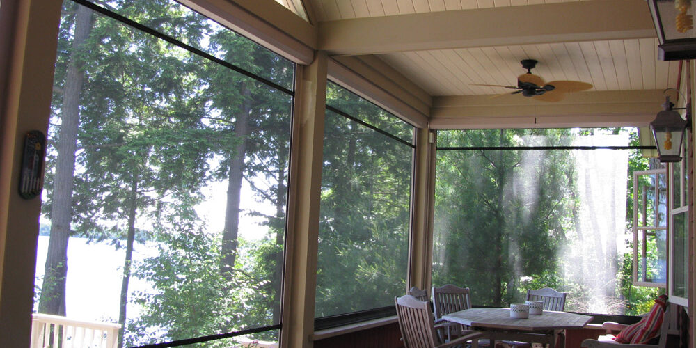 Cozy screened porch with a round table and chairs overlooking trees.
