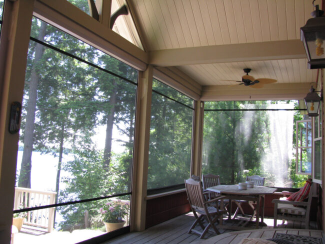 Cozy screened porch with a round table and chairs overlooking trees.