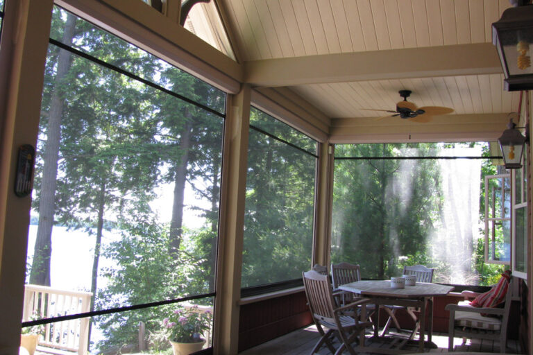 Cozy screened porch with a round table and chairs overlooking trees.