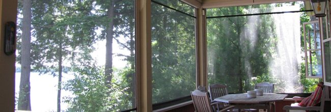 Sunlit room with large windows overlooking green trees.