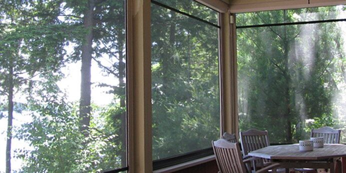 Sunlit room with large windows overlooking green trees.