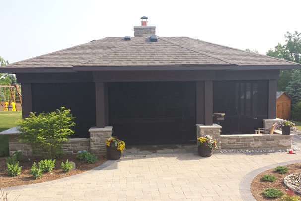 Modern house exterior with dark garage doors and stone pillars.
