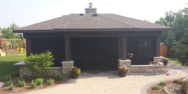 Modern house exterior with dark garage doors and stone pillars.