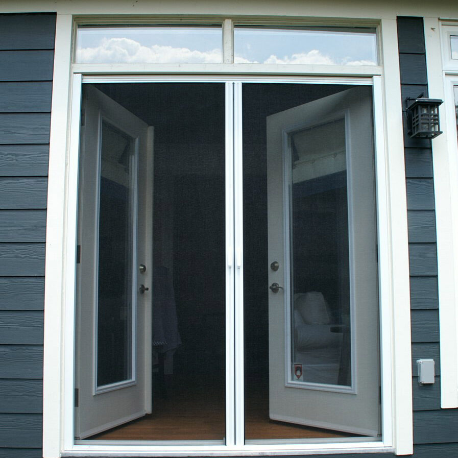 White French doors open onto a porch with a view of a lawn and trees.