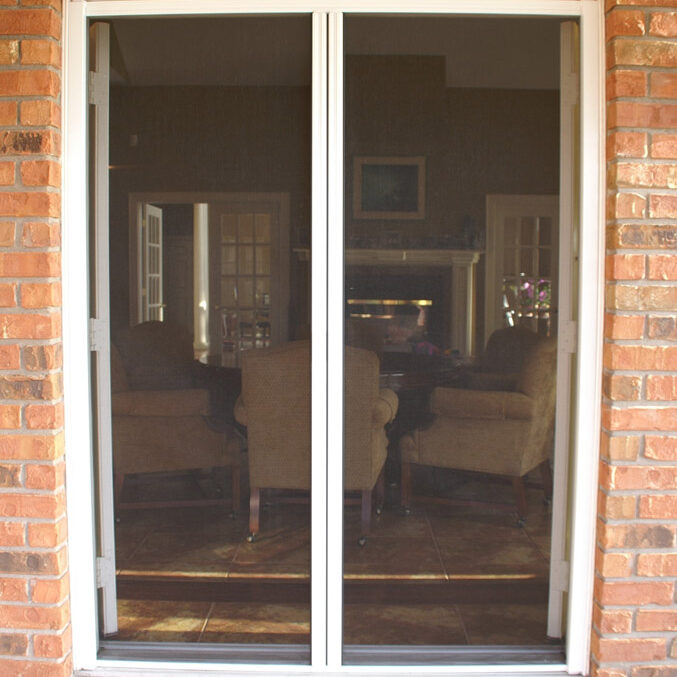 A mesh screen door installed in a brick patio doorway.