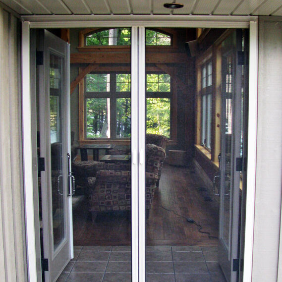 Sliding glass door leading to a cozy sunroom with wooden furniture.