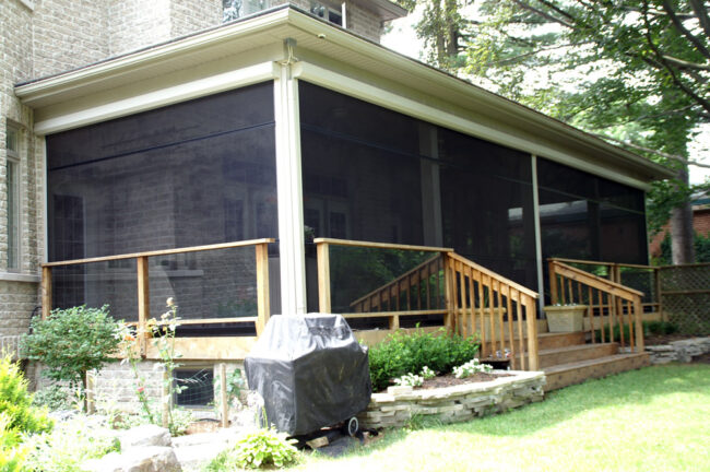A screened porch with a grill on the patio outside.