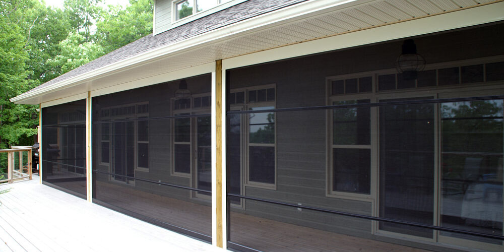 A porch enclosed with black mesh screening and wooden posts.