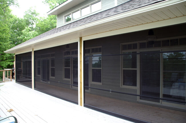 A porch enclosed with black mesh screening and wooden posts.