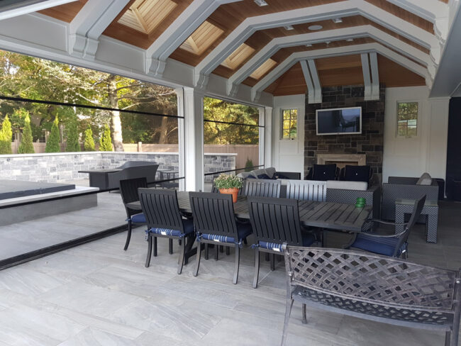 Cozy outdoor patio with dining and lounge seating under a wooden roof.