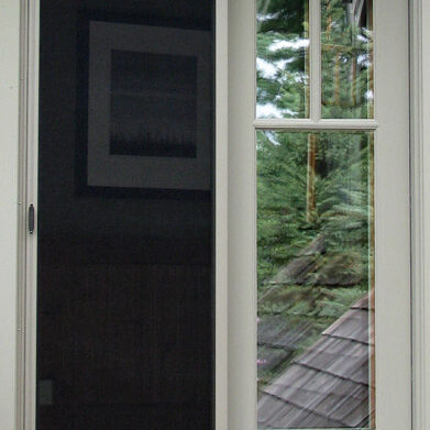 Window view showing a blurry outdoor scene with trees and a rooftop.