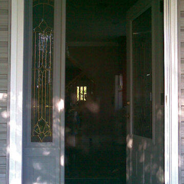 Open front door revealing a dimly lit interior with reflections.