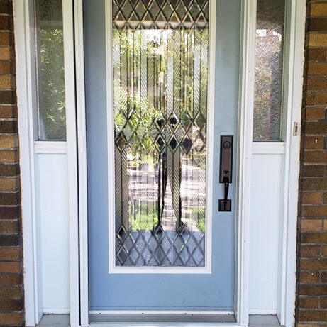 A front door with decorative glass panels and a modern handle lock.