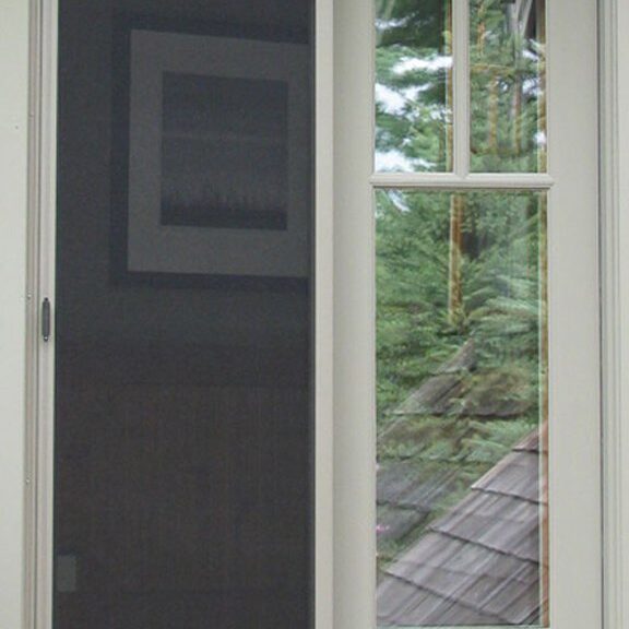 White-framed window with a black screen and nature view outside.