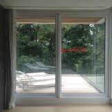 Large glass sliding doors open to a green outdoor space.