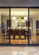 Modern dining room seen through large glass doors at night.