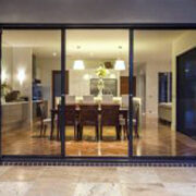 Modern dining room seen through large glass doors at night.