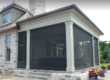 Modern porch with retractable black mesh screens and stone base.