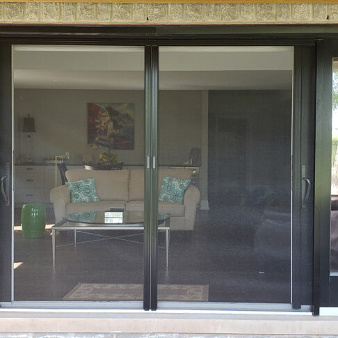 Modern sliding glass door with a mesh screen in a living room.