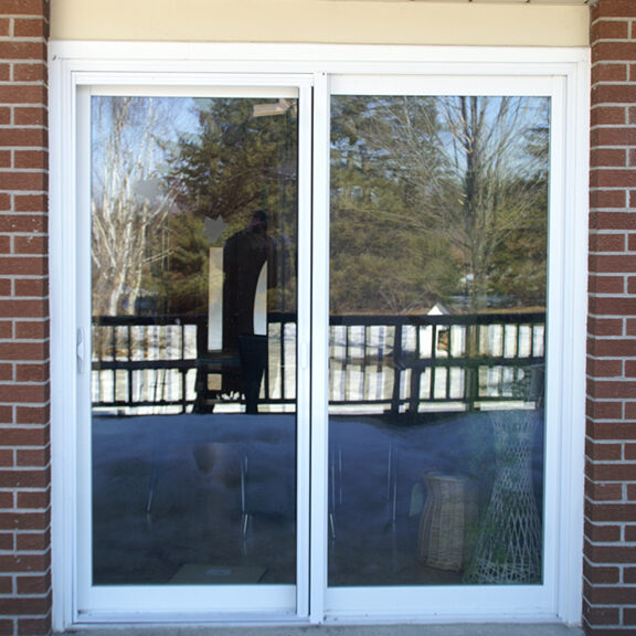 Sliding glass door reflecting a person and outdoor scenery.